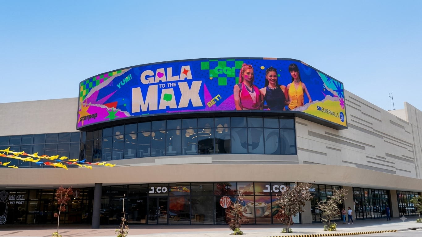 A curved outdoor digital billboard mounted on a shopping mall displays a colorful promotional advertisement.